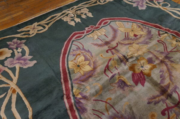 Stylized floral rug in deep teal, cream, and purple accents lying on a brown hardwood floor.