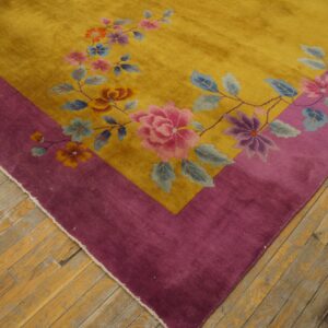 High-pile gold rug with a magenta border and colorful floral pattern on aged hardwood floors.