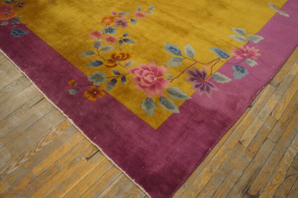 High-pile gold rug with a magenta border and colorful floral pattern on aged hardwood floors.