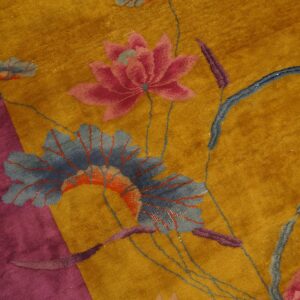 Velvety gold rug with a magenta border featuring a large floral pattern of pink blossoms and blue leaves.