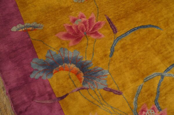 Velvety gold rug with a magenta border featuring a large floral pattern of pink blossoms and blue leaves.