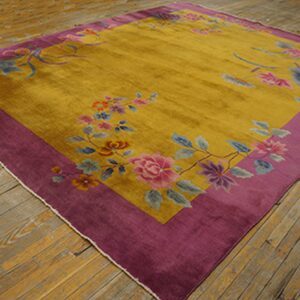 Multicolored floral rug in gold and deep purple displayed on rustic wooden floorboards.
