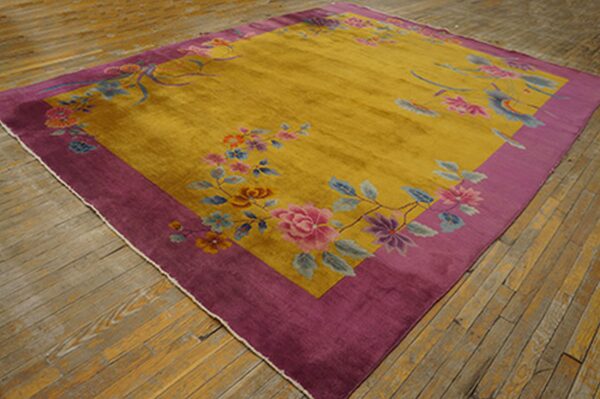Multicolored floral rug in gold and deep purple displayed on rustic wooden floorboards.