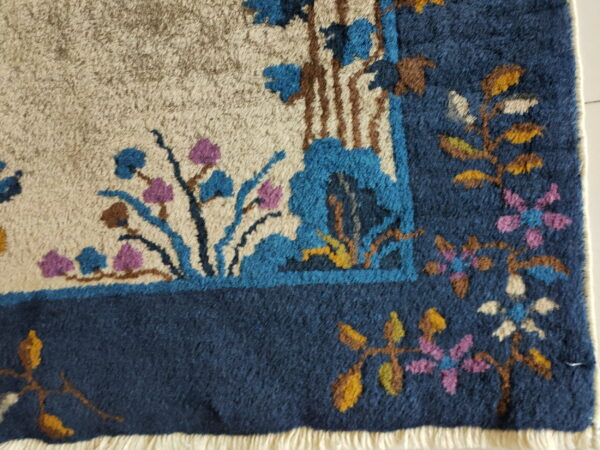 Textured high-pile rug detail showing abstract blue, brown, and purple florals on a cream background.