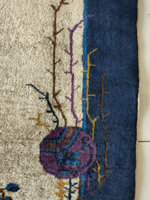 High-pile rug texture showing abstract branches and a purple circle motif on beige and navy fields.