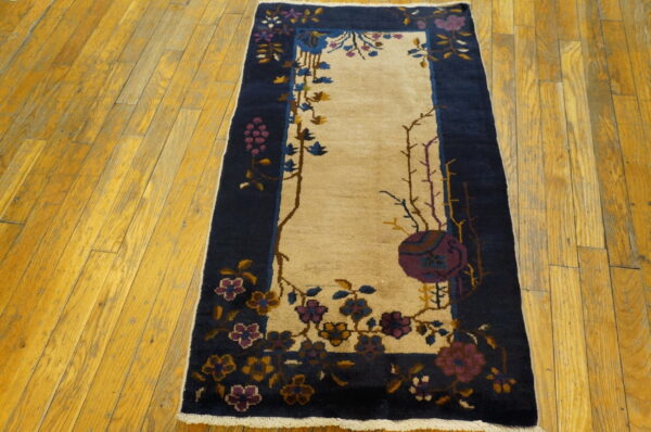 A navy and cream runner rug with purple, blue, and gold floral patterns rests on yellow hardwood.