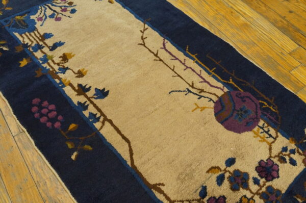 Navy and beige runner rug on wood floor with purple, blue, and yellow floral vine details.