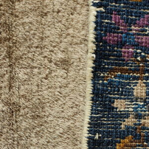 Close-up of a brown shaggy rug texture beside a patterned navy rug edge with purple and brown accents.