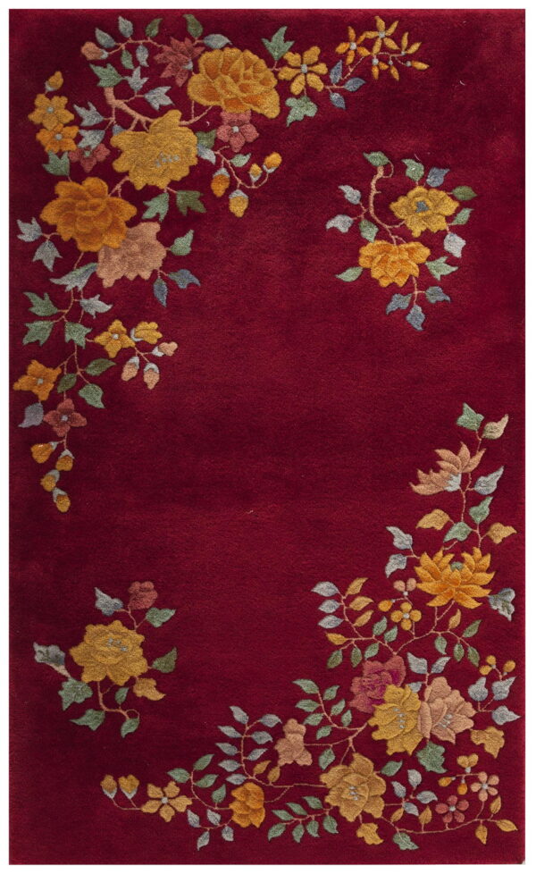 Deep red rug with plush pile, featuring yellow, green, and pink floral clusters along the border.