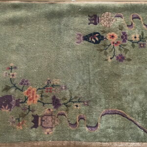 Olive green high-pile rug featuring scattered pink, orange, and purple stylized floral and ribbon patterns.