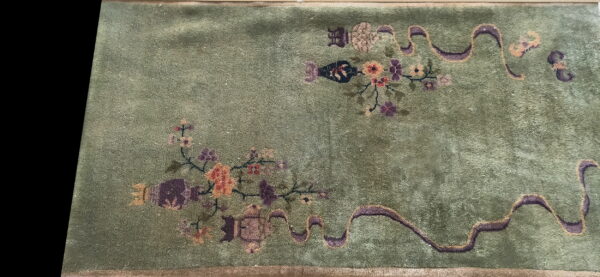 Olive green high-pile rug featuring scattered pink, orange, and purple stylized floral and ribbon patterns.