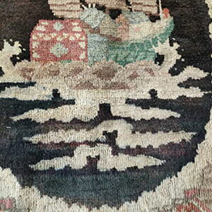 Muted color, thick pile rug detail featuring abstract motifs in dark brown, cream, and reddish tones.