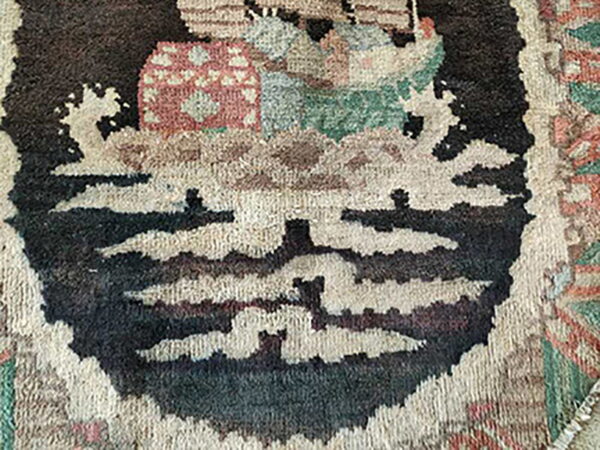 Muted color, thick pile rug detail featuring abstract motifs in dark brown, cream, and reddish tones.