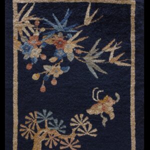 Dark blue rug featuring a tan geometric border and colorful botanical patterns in gold, rust, and blue.