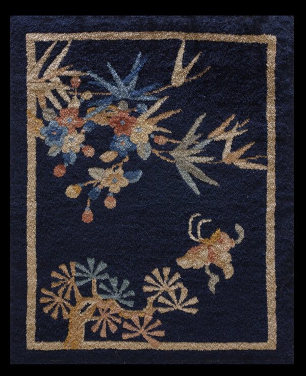 Dark blue rug featuring a tan geometric border and colorful botanical patterns in gold, rust, and blue.