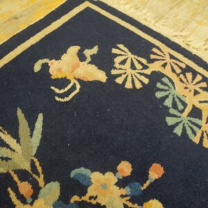 A navy blue rug corner features pale yellow and green botanical motifs on distressed wooden floorboards.
