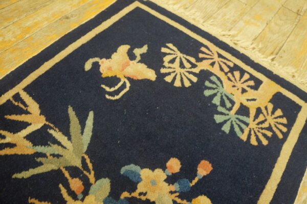 A navy blue rug corner features pale yellow and green botanical motifs on distressed wooden floorboards.