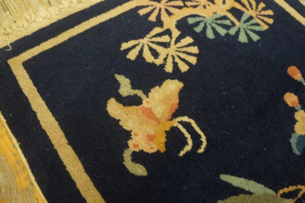 High-pile navy rug featuring a beige border and gold, peach, and green stylized floral patterns.