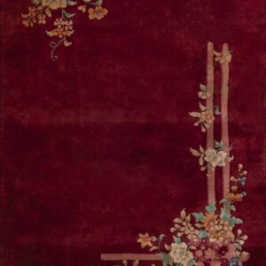 Deep red rug featuring stylized pink, blue, and gold floral corner motifs with lattice accents.