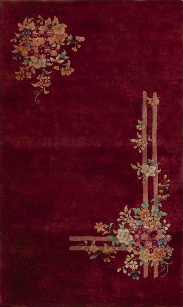 Deep red rug featuring stylized pink, blue, and gold floral corner motifs with lattice accents.