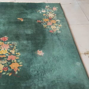 Green area rug featuring clustered floral patterns in peach and yellow on light tile.