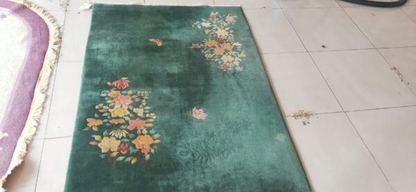 Green area rug featuring clustered floral patterns in peach and yellow on light tile.