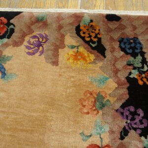 High-pile tan rug featuring large blue, purple, and orange floral motifs bordering black and brown geometric patterns.