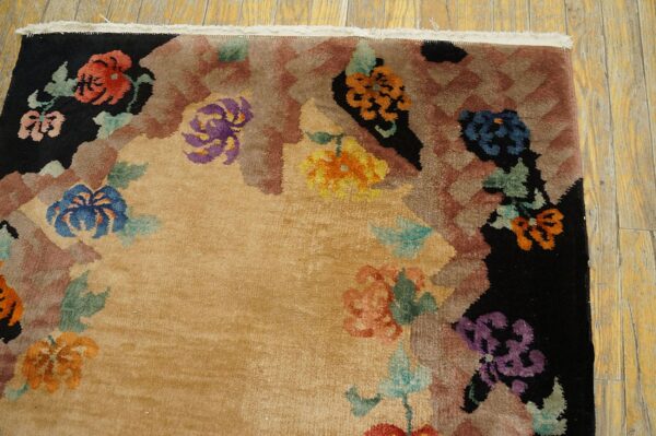 High-pile tan rug featuring large blue, purple, and orange floral motifs bordering black and brown geometric patterns.