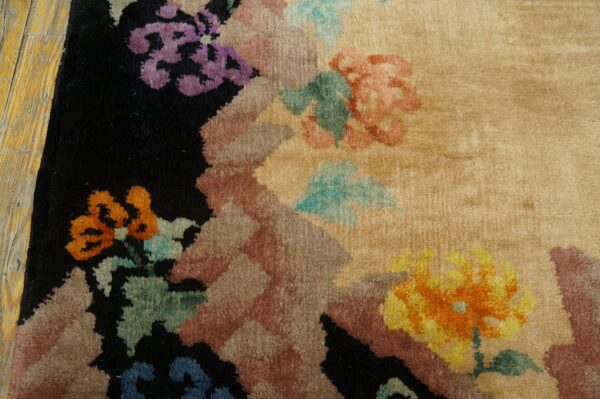 Plush beige rug with colorful abstract floral motifs, including purple and orange, next to worn wood planks.