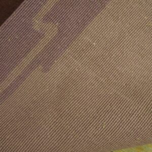 Dusty mauve twill-woven rug backing is folded back, exposing an orange and purple floral pattern on the face.