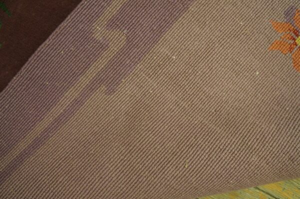 Dusty mauve twill-woven rug backing is folded back, exposing an orange and purple floral pattern on the face.