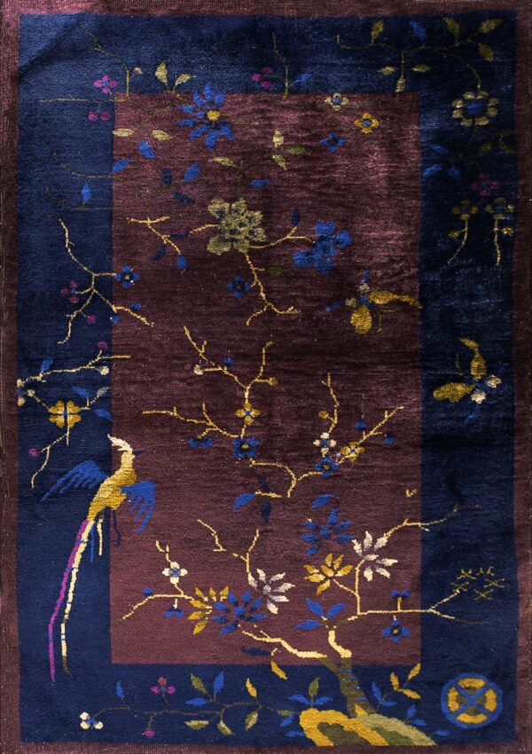 Navy and burgundy rug featuring colorful branches, flowers, and a stylized bird motif.