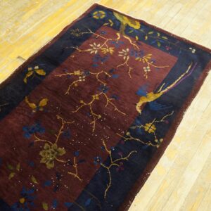 Burgundy and navy runner with floral and bird patterns rests on a distressed light yellow wood floor.