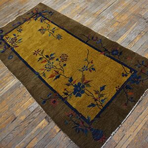 Mustard gold rug with olive border and navy floral patterns rests on distressed wooden planks.