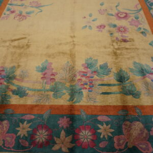 Gold rug with detailed pink and teal floral vines, featuring wide rust and deep teal decorative borders.