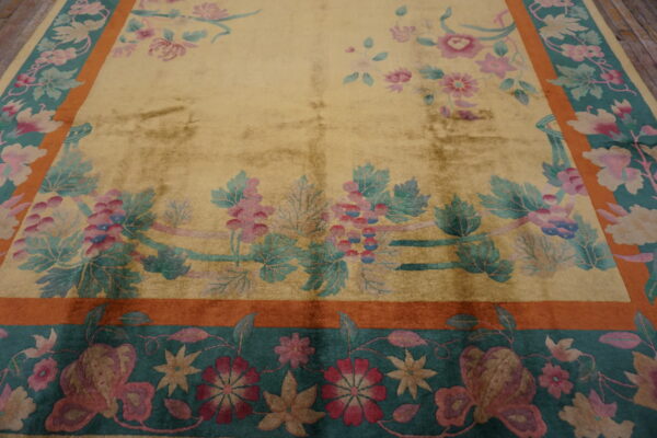 Gold rug with detailed pink and teal floral vines, featuring wide rust and deep teal decorative borders.