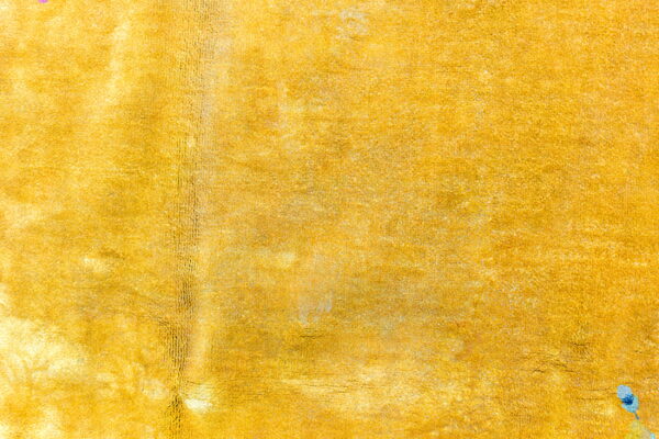 Textured, high-saturation golden yellow rug surface with visible pile variations and sheen.