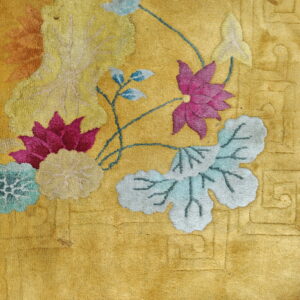 Golden yellow rug with detailed pink, blue, and teal floral motifs and embossed geometric patterns in the border area.