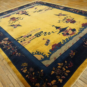 Bright yellow rug with a navy floral border and center crane motifs on weathered wood floors.
