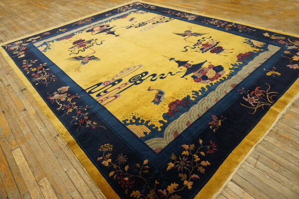 Bright yellow rug with a navy floral border and center crane motifs on weathered wood floors.