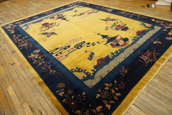 Gold rug with a navy blue border displays stylized cranes and floral motifs on aged wood flooring.