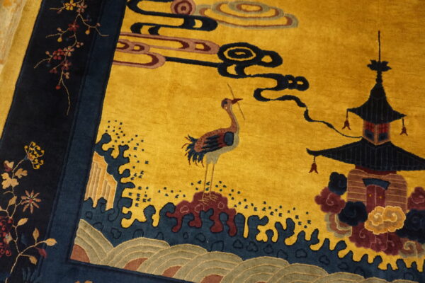 Golden yellow rug detailed with a crane, pagoda, stylized clouds, and a navy blue floral border.