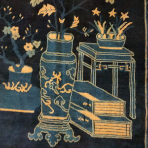 Deep blue high-pile rug displaying an intricate gold and teal pattern of antique vases and stylized flora.