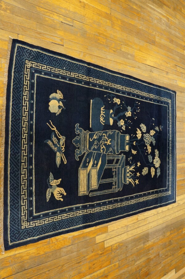 Dark blue runner rug with pale yellow floral and lantern designs rests on golden hardwood flooring.