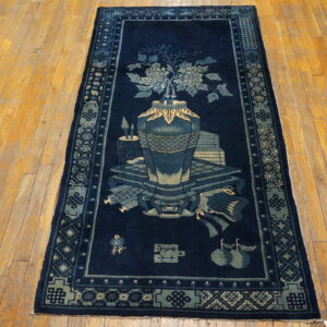 Navy blue rug runner with a pale blue vase and floral motif rests on distressed golden hardwood planks.