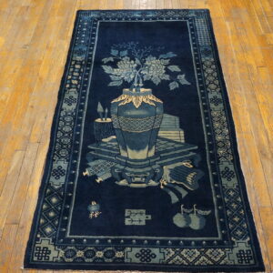 Dark blue runner rug featuring a vase of flowers and symbolic objects, displayed on distressed wood floors.