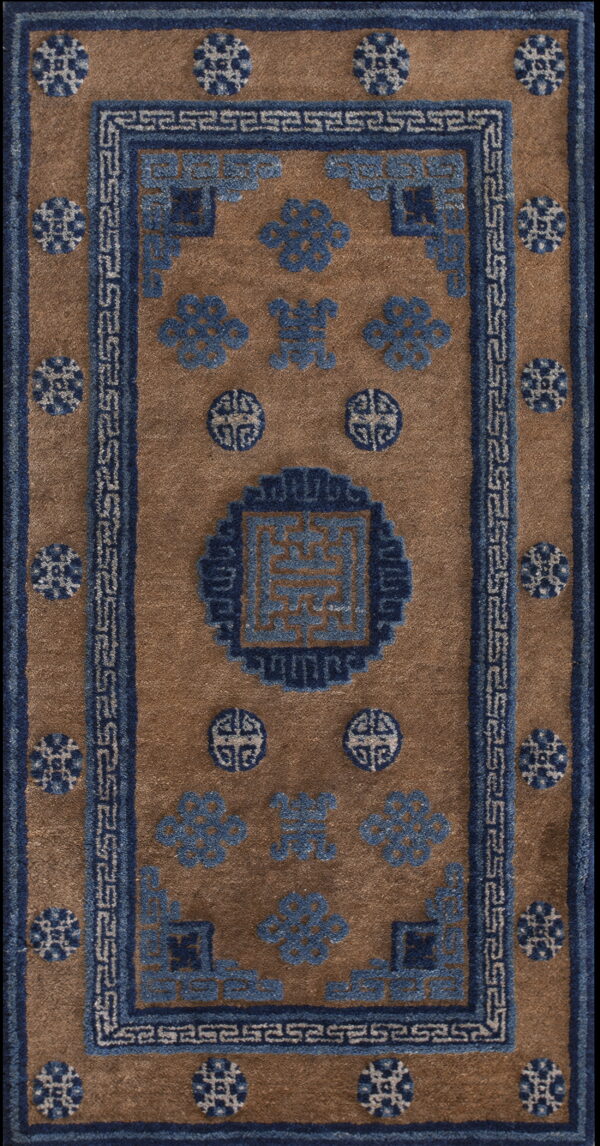 Brown rug with a central blue geometric medallion, scattered blue motifs, and fretwork border design.