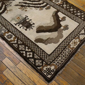 Textured brown and cream rug with geometric borders and stylized figures rests on rustic wood flooring.