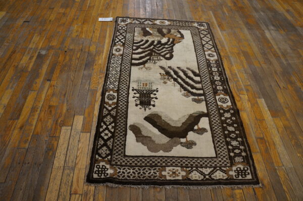 Runner rug with abstract brown and cream motifs and geometric borders on distressed wood flooring.