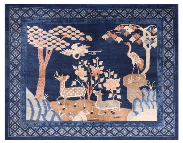 A dark blue rug featuring a pastoral scene with deer, cranes, and trees in pink and tan, surrounded by a geometric border.
